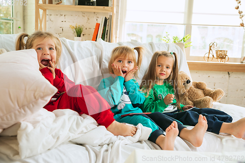 Image of Little girls in soft warm pajamas playing at home