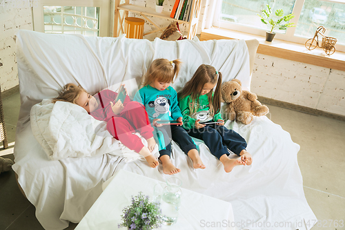 Image of Little girls in soft warm pajamas playing at home