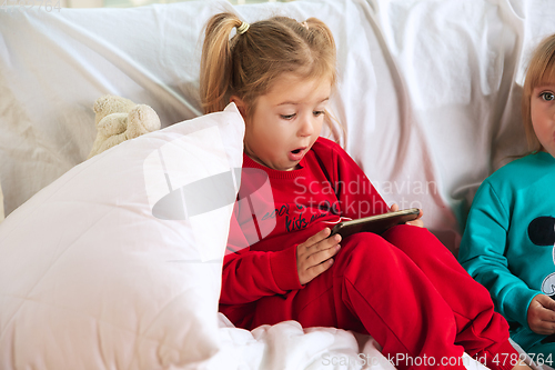 Image of Little girls in soft warm pajamas playing at home