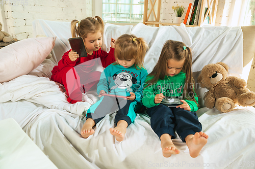 Image of Little girls in soft warm pajamas playing at home