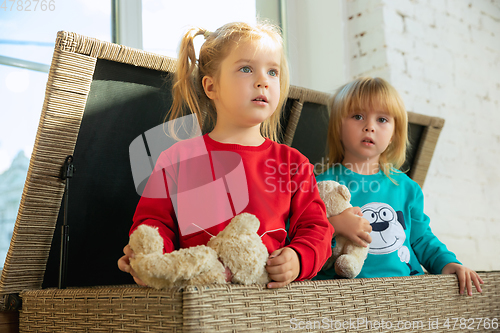 Image of Little girls in soft warm pajamas playing at home