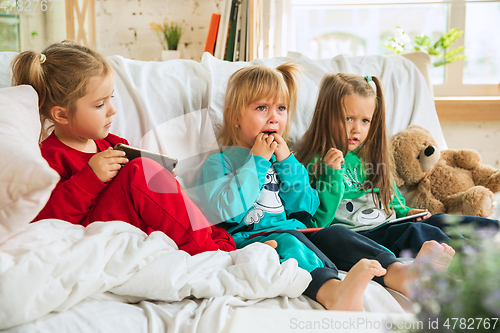 Image of Little girls in soft warm pajamas playing at home