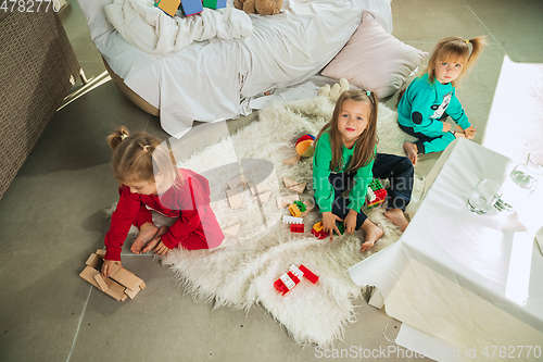 Image of Little girls in soft warm pajamas playing at home