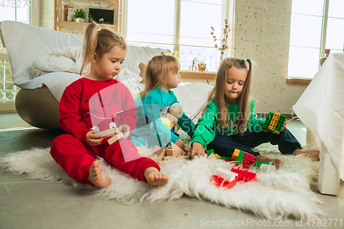 Image of Little girls in soft warm pajamas playing at home