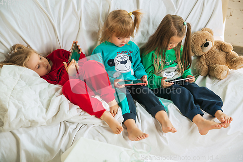 Image of Little girls in soft warm pajamas playing at home
