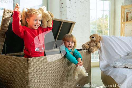 Image of Little girls in soft warm pajamas playing at home