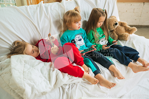 Image of Little girls in soft warm pajamas playing at home