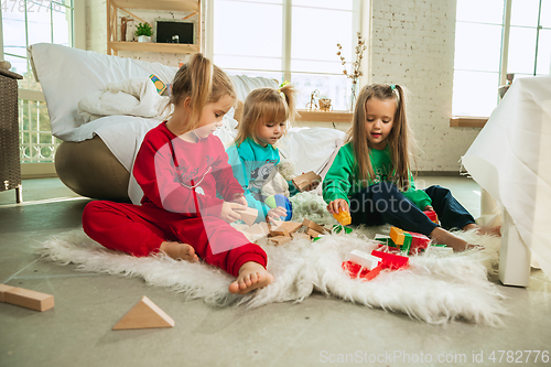 Image of Little girls in soft warm pajamas playing at home