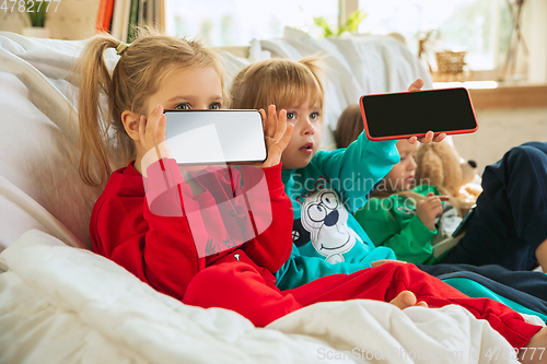 Image of Little girls in soft warm pajamas playing at home