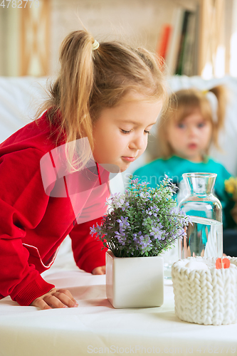 Image of Little girls in soft warm pajamas playing at home