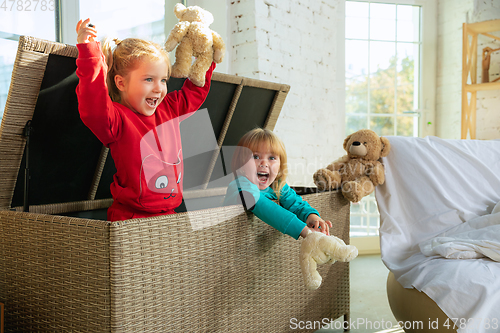 Image of Little girls in soft warm pajamas playing at home