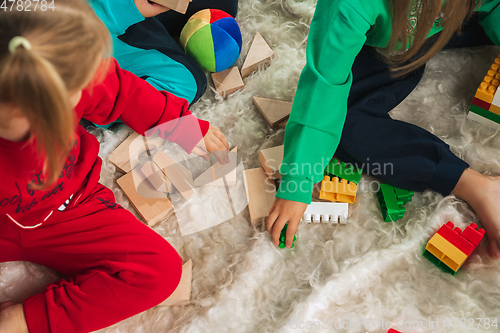 Image of Little girls in soft warm pajamas playing at home