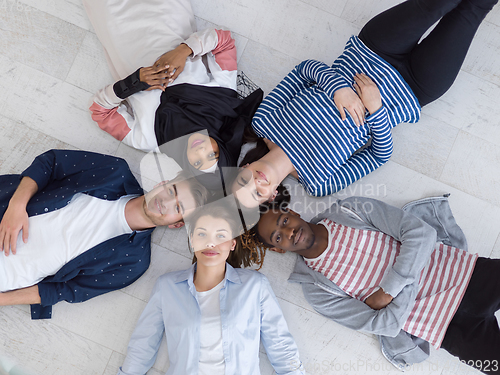 Image of top view of a diverse group of people lying on the floor and symbolizing togetherness