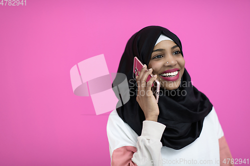 Image of afro woman uses a cell phone in front of a pink background