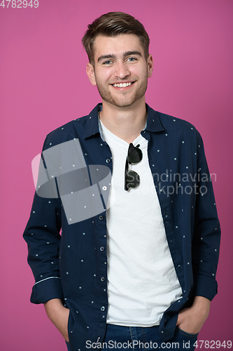 Image of a portrait of a young man wearing a blue shirt and posing in front of a pink background 