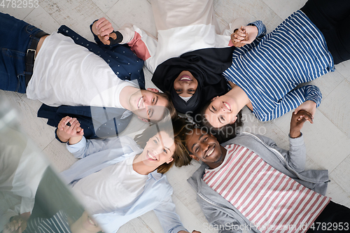 Image of top view of a diverse group of people lying on the floor and symbolizing togetherness