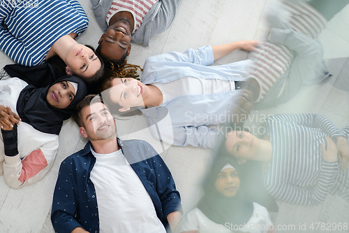 Image of top view of a diverse group of people lying on the floor and symbolizing togetherness