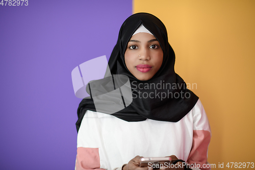 Image of afro woman uses a cell phone in front of a pink background