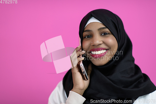 Image of afro woman uses a cell phone in front of a pink background