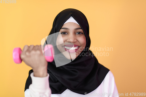 Image of afro muslim woman promotes a healthy life, holding dumbbells in her hands