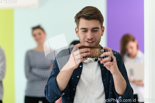 Image of guy with the beautiful smile in the blue attractive shirt i use my cell phone and headphones