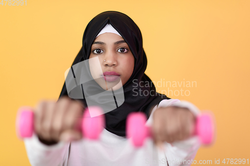 Image of afro muslim woman promotes a healthy life, holding dumbbells in her hands