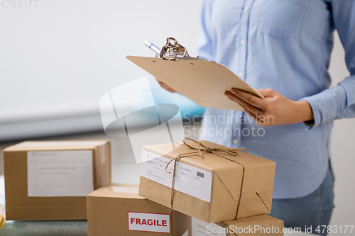 Image of woman with parcels and clipboard at post office