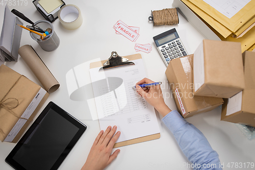 Image of woman with parcels and clipboard at post office