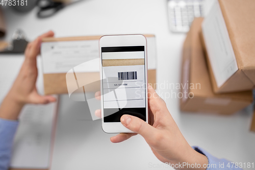 Image of hands with smartphone scans barcode on parcel box