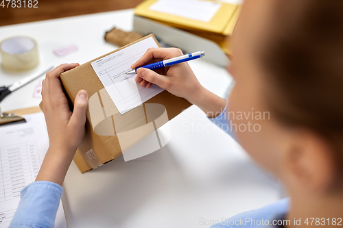 Image of close up of woman filling postal form at office