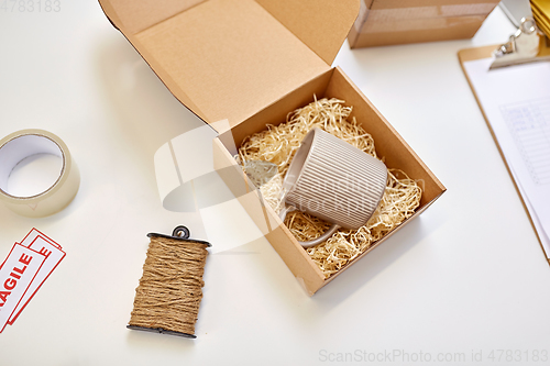 Image of parcel with straw filler and mug at post office