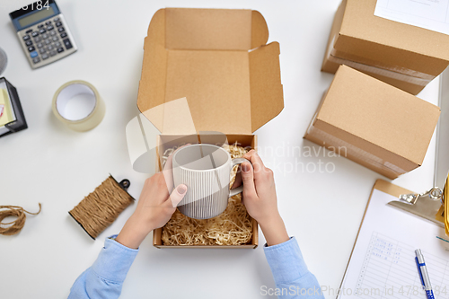 Image of hands packing mug to parcel box at post office