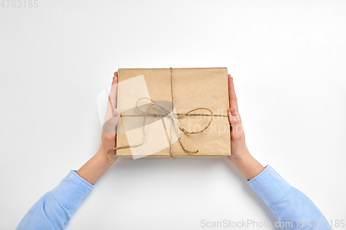 Image of hands with parcel box tied by rope at post office