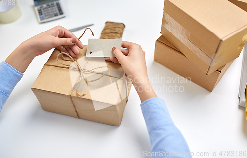 Image of hands tying name tag to parcel box at post office