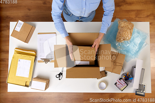 Image of woman packing fragile parcel boxes at post office