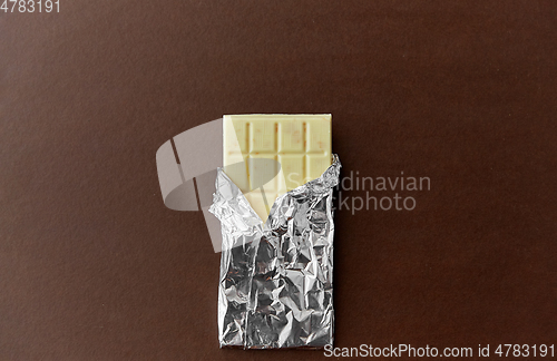 Image of white chocolate bar in foil wrapper on brown