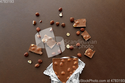 Image of milk chocolate bar with hazelnuts in foil wrapper