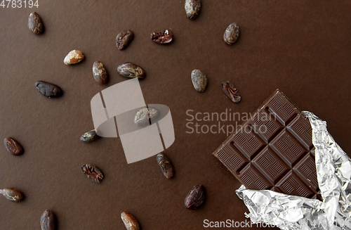 Image of dark chocolate bar in foil wrapper and cocoa beans
