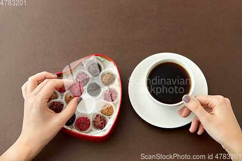 Image of hands, candies in heart shaped box and coffee cup