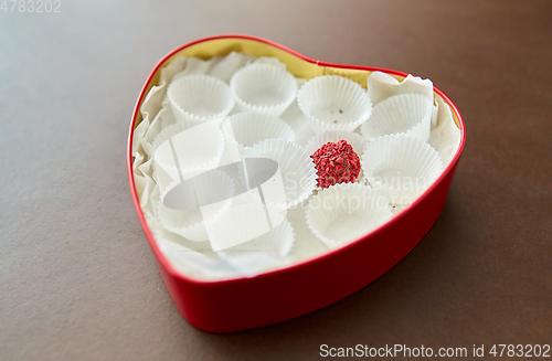 Image of one candy in red heart shaped chocolate box
