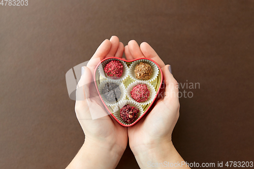 Image of hands with candies in heart shaped chocolate box