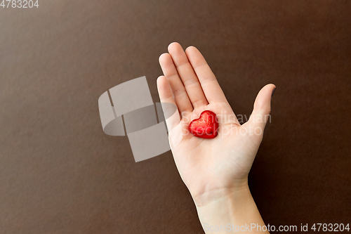 Image of hand with red heart shaped chocolate candy