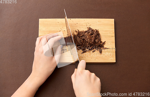 Image of hands chopping chocolate chips on wooden board