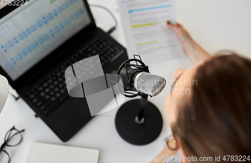 Image of woman with microphone recording podcast at studio