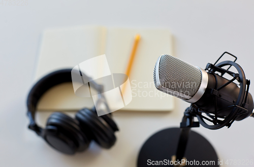 Image of headphones, microphone and notebook with pencil