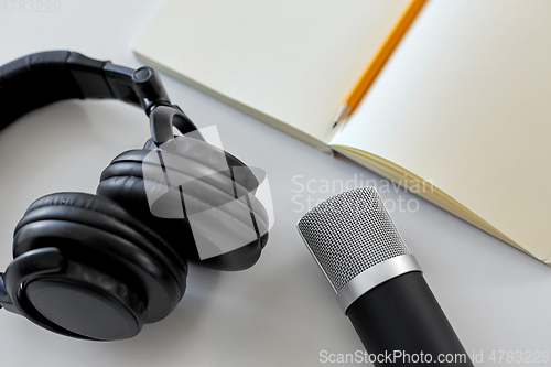 Image of headphones, microphone and notebook with pencil