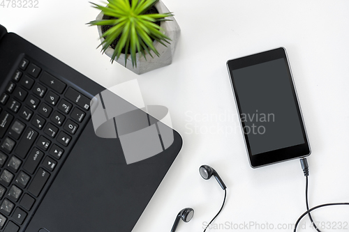 Image of close up of laptop, smartphone and earphones