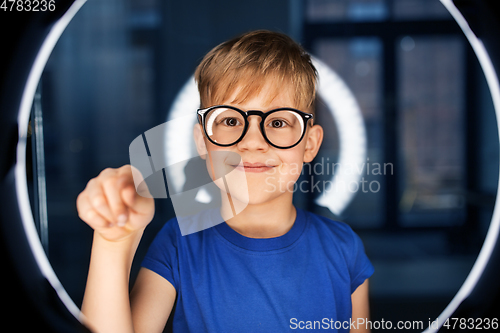 Image of boy in glasses over illumination in dark room