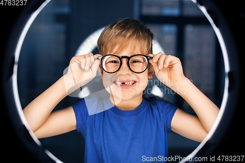 Image of boy in glasses over illumination in dark room