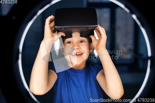 Image of boy in vr glasses over illumination in dark room